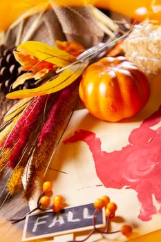 Red hand turkey on vanilla construction paper with a small orange pumpkin, brown and red foliage, and a sign that says "FALL" on it