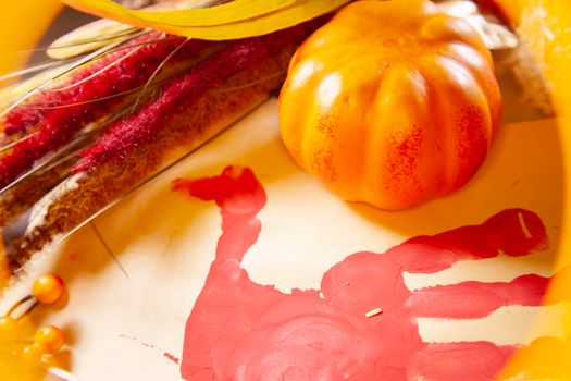 Red hand turkey on vanilla construction paper with a small orange pumpkin, and brown and red foliage