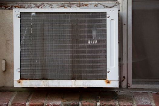 Air conditioner in the window of a red brick building, bolstered by styrofoam