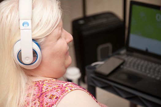 Blind woman listening to headphones while on the computer