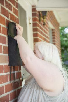 Albino woman carefully checking her mailbox for mail