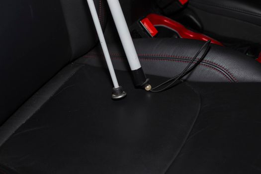 Folded white cane in the passenger seat of a vehicle