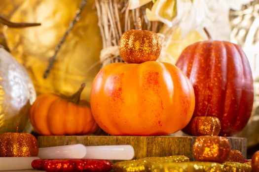 Small orange pumpkins, small red pumpkin, small orange glitter pumpkins, a large silver pumpkin, red, yellow, and orange glitter leaves, and dried sunflowers against a golden background