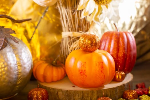 Small orange pumpkins, small red pumpkin, small orange glitter pumpkins, yellow, red, and orange glitter leaves, silver pumpkin, and dried sunflowers against a golden background