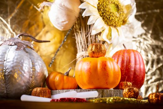 Small orange pumpkins, small red pumpkin, small orange glitter pumpkins, a large silver pumpkin, red, yellow, and orange glitter leaves, and dried sunflowers against a golden background