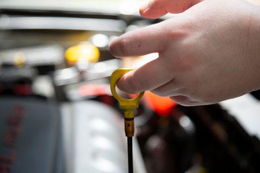 Woman checking the transmission fluid in an automobile