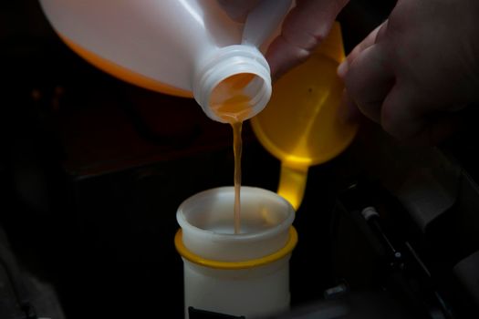 Windshield washer fluid being poured into the container in an automobile