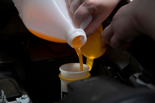 Windshield washer fluid being poured into the container in an automobile