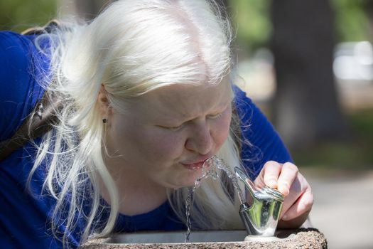 Close up of a woman drinking from a water fountain outside