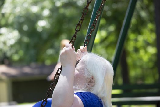 Adult albino woman enjoying playing on a park swing