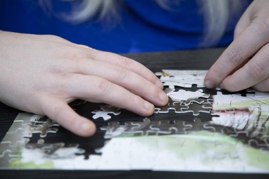 Woman connecting completed sections of a puzzle together