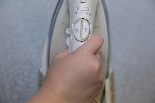 Woman grabbing a steaming iron from its holster on the wall