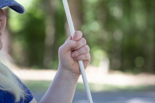 Blind woman in a baseball cap holding a cane outside