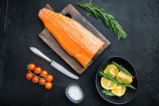 Whole raw salmon fillet on black background, flat lay.