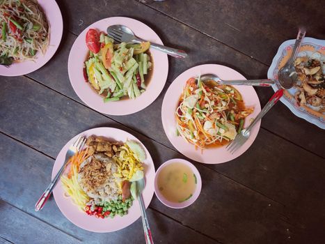 Top view Thai food on table: Eating north eastern foods (SOM TUM - Spicy Papaya Salad, Sticky rice). Local and traditional way. Thai Food Background. enjoy eating concept