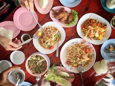 Top view Thai food on table: Eating north eastern foods (SOM TUM - Spicy Papaya Salad, Sticky rice, NUM TOK - Spicy Soup). Local and traditional way. Thai Food Background. enjoy eating concept