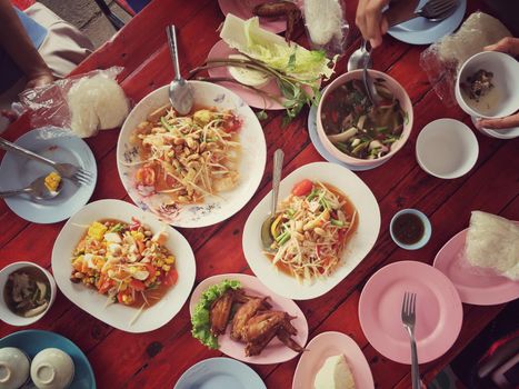 Top view Thai food on table: Eating north eastern foods (SOM TUM - Spicy Papaya Salad, Sticky rice, NUM TOK - Spicy Soup). Local and traditional way. Thai Food Background. enjoy eating concept