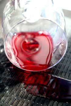 A glass of spilled wine lies on a dark embossed background