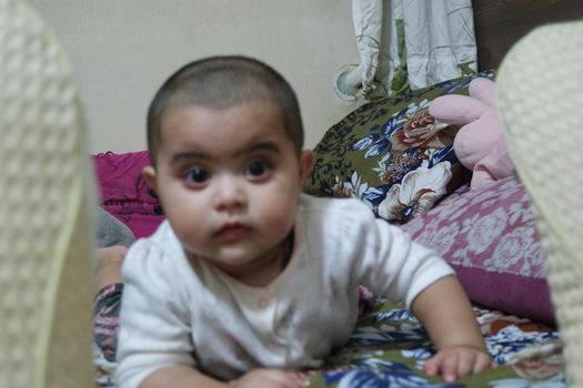 Baby with bald head staring at camera. Baby girl with lovely face, big eyes and cute face gesture.