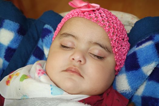 Sleeping baby with red head band. Baby girl with lovely face, big eyes and cute face gesture.