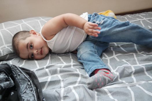 Baby girl with lovely face, big eyes and cute face gesture. Baby girl with jeans playing on bed.