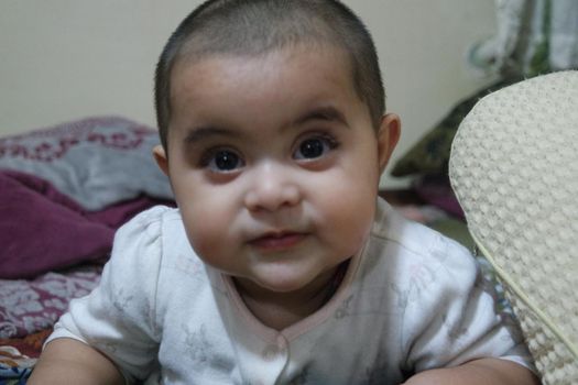 Baby girl with lovely face, big eyes and cute face gesture. Baby with bald head staring at camera.