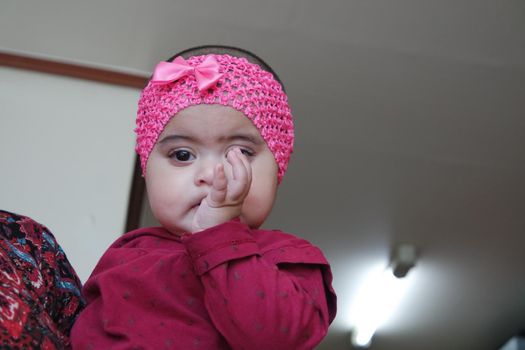 Baby with finger in mouth. Baby girl with lovely face, big eyes and cute face gesture.