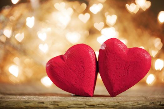 Two red wooden hearts symbol of love on background with beautiful bokeh party lights, Saint Valentine Day celebration