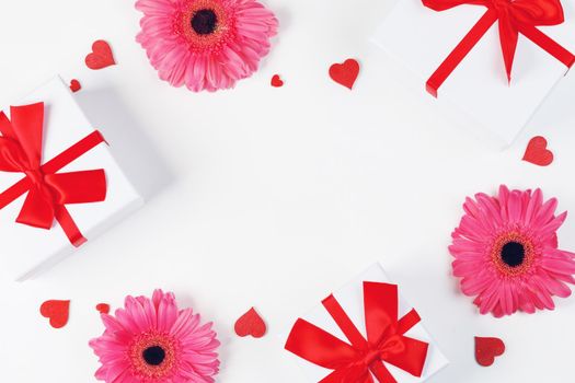 Pink gerbera flowers gifts and red hearts composition on white background top view with copy space. Valentine's day, birthday, wedding, Mother's day concept. Copy space