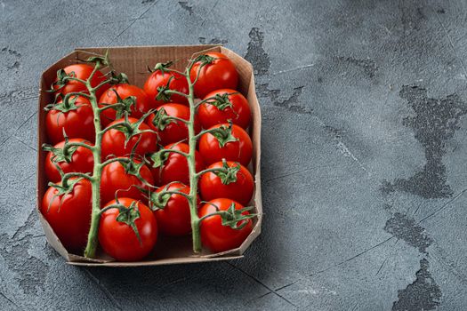 Ripe cherry tomatoes in tray, on gray background with copy space for text