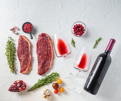 Picanha steak with bottle of red wine and glass, herbs and pomegranate top view over white textured background . Big size