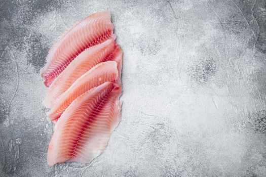 Tilapia fish, skinless meat, on gray background, top view with copy space for text