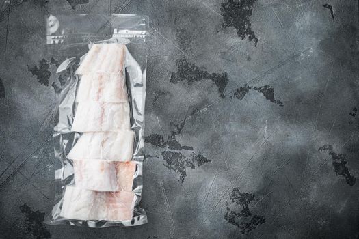 Raw haddock fish skinless plastic vacuum packaged, on gray background, top view with copy space for text