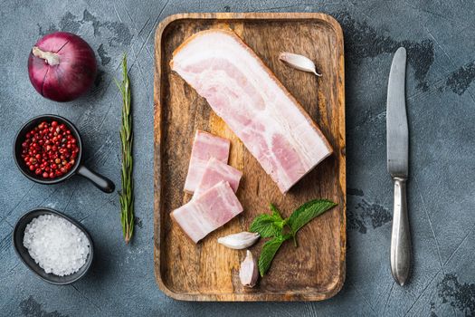 Bacon pancetta cut and sliced with herbs on grey textured background, top view.