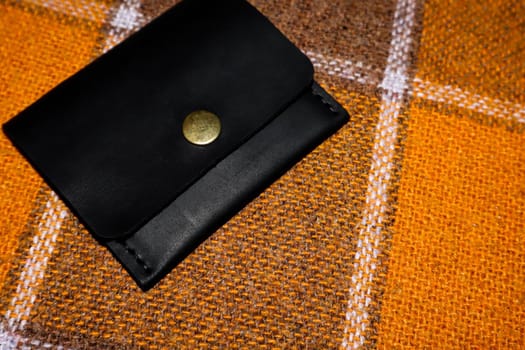 The leather wallet is sewn with white threads on an orange cover in a cell