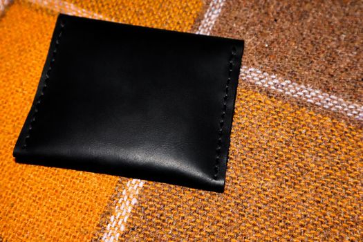 The leather wallet is sewn with white threads on an orange cover in a cell
