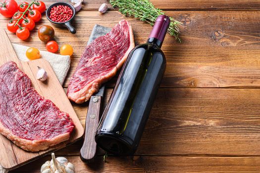 Picanha organic beef steaks over old american butcher cleaver with seasonings and red wine bottle on wooden table. Side view with space for text