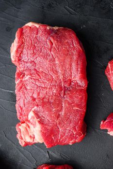 Organic rump beef steaks, top view on black textured table.