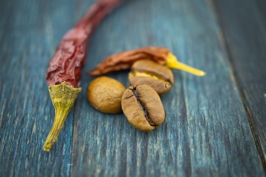 Dried red chili pepper and roasted coffee beans on wooden background. Macro photo