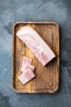Bacon pancetta cut and sliced on grey textured background, top view.