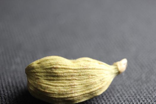 Closeup top view of dried green Elettaria cardamomum fruits with seeds, cardamom spice scattered on white background