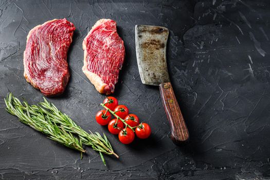 Picanha raw beef steaks with herbs and old butcher cleaver on black textured background, side view space for text