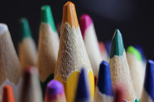 Close-up view of bright colored multicolor pencils on black background