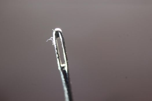 Macro photograph of sewing needle. Small needle with empty eyelet, isolated over the black background.