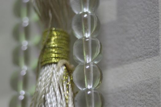 Macro photograph with selective focus of glass shiny prayer beads or rosary with copy space for text. Religion concept of ramadan or Eid for muslims.