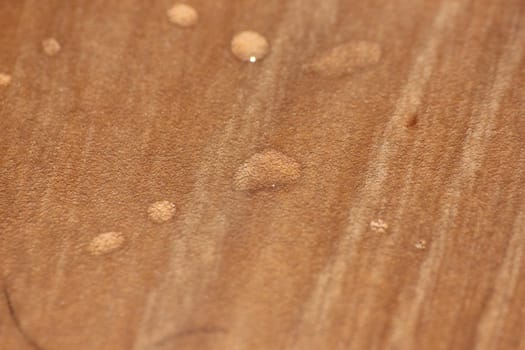 Closeup selective focus view of water drops on wooden floor. Abstract raindrops pattern on wooden board