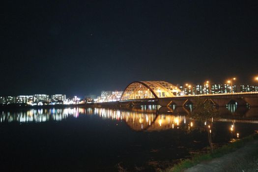 Night view of a beautiful scene of bridge over sea water in the evening time with colorful lights.