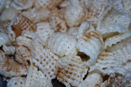 Closeup view of freshly fried chips as fast food for tea break. Potato chips with spices sprinkled on it. Fast food background for advertisements.