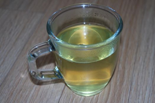 Glass cup having brewed fragrant green tea or qehwa or qahwa on the wooden floor. It is served with sugar or honey and nuts