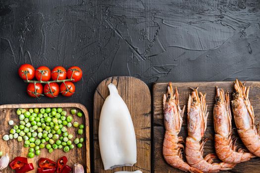 Traditional valenciana paella seafood ingredients with prawns, mussels, rice and spices on black concrete surface, flat lay with copy space, food photo.